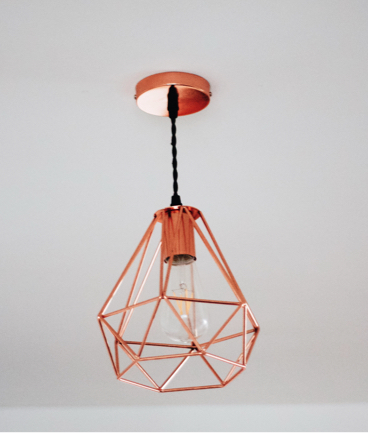 A geometric pendent light with a cooper finish and edison-style lightbulb.